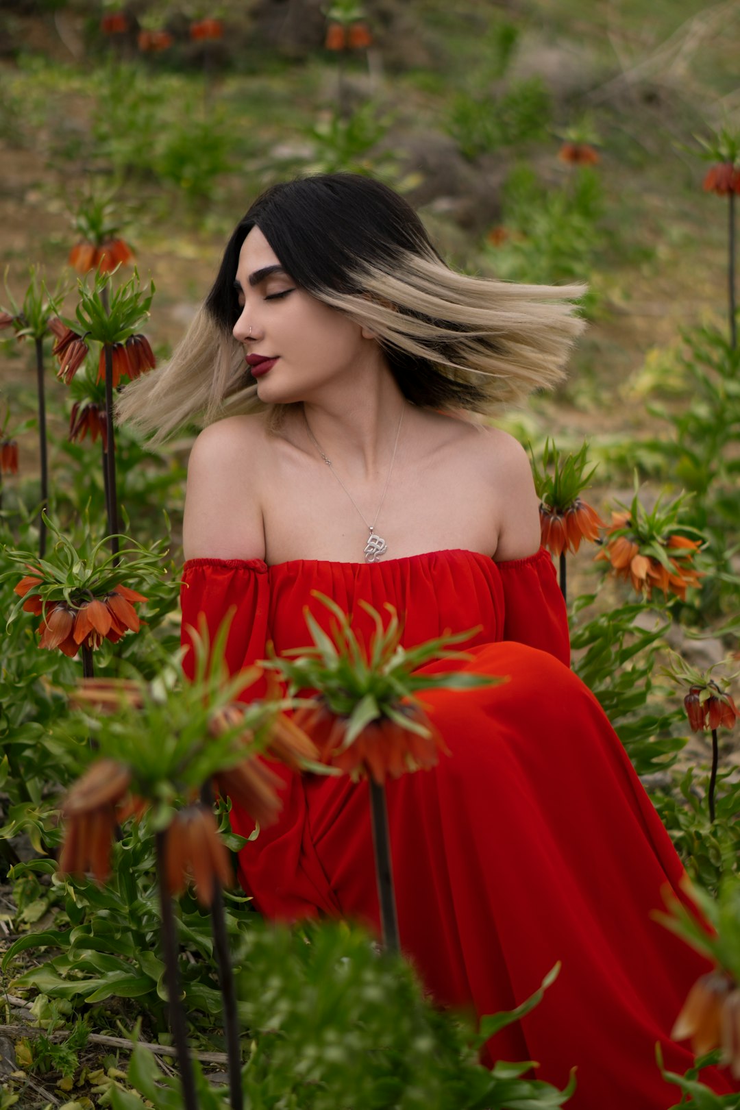 woman in red off shoulder dress holding red flowers
