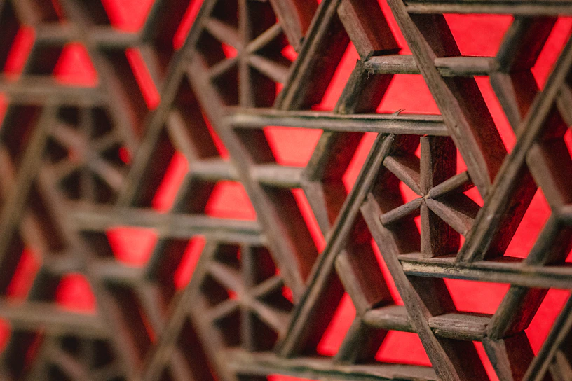 Close-up of colorful string art forming a geometric pattern on a wooden board