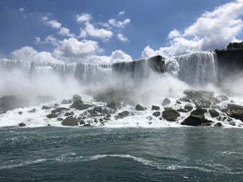 water falls under blue sky during daytime