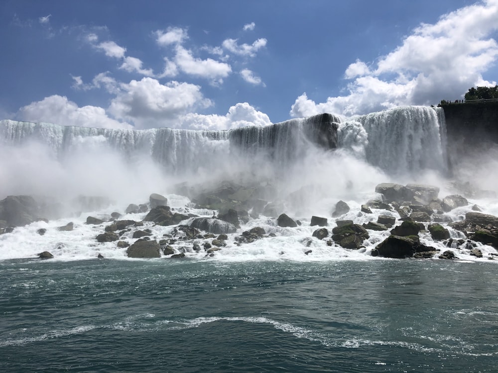 water falls under blue sky during daytime