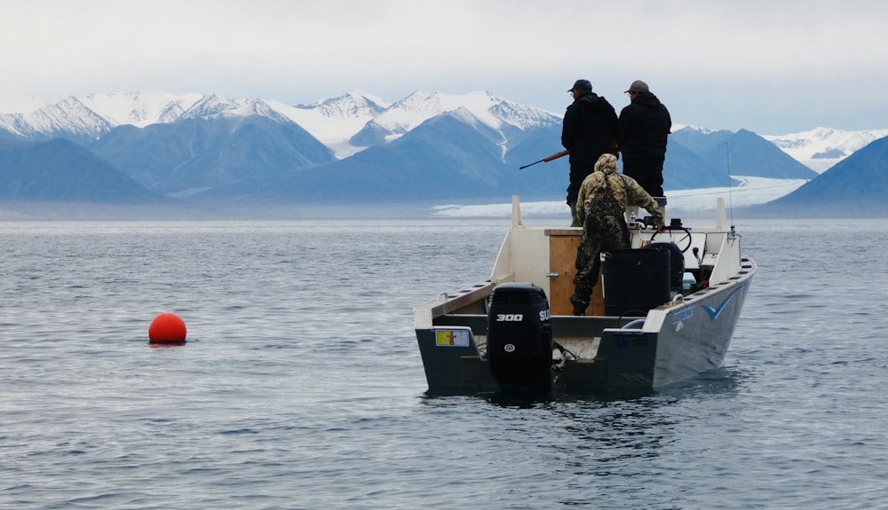 2 men in black jacket sitting on boat on lake during daytime