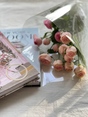 A delicate bouquet of pink and white flowers with soft petals surrounding a stack of colorful teen books.
