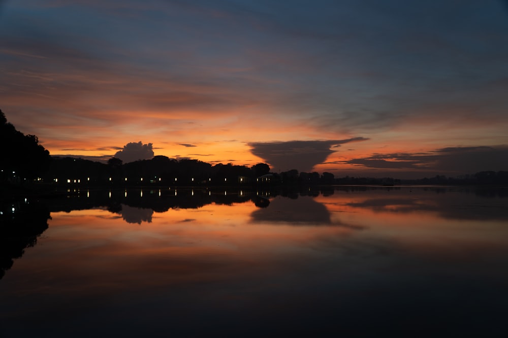 silhouette of building near body of water during sunset