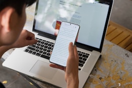 Person working comfortably from home, using a laptop and smartphone side by side.