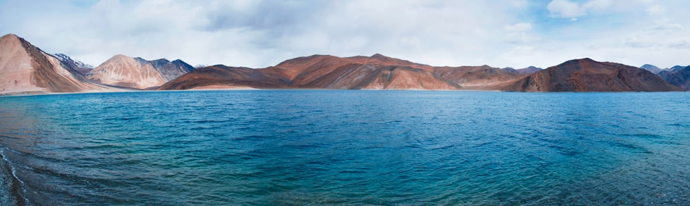 brown mountain beside body of water during daytime