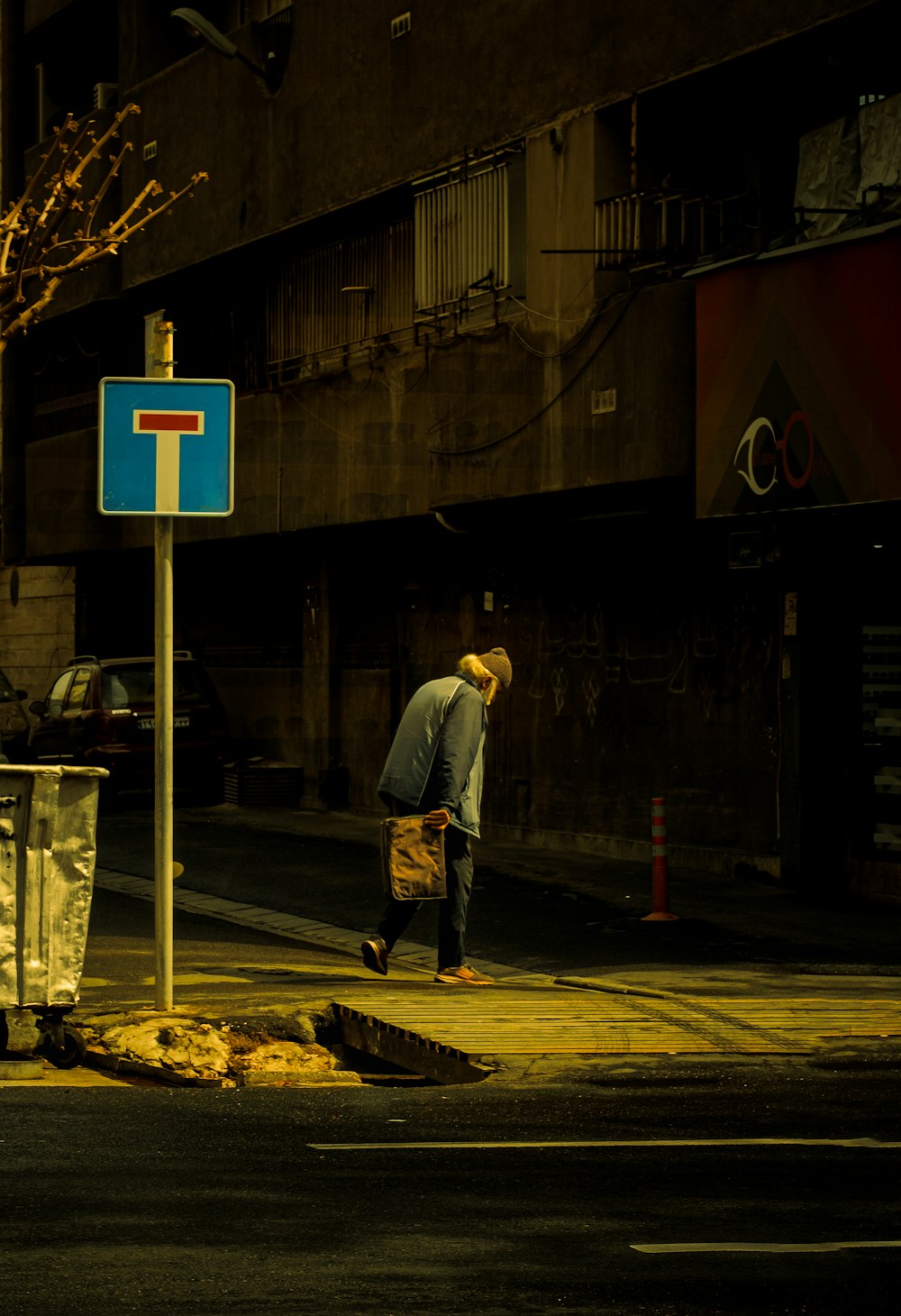 man in white long sleeve shirt and blue denim jeans standing on sidewalk during daytime