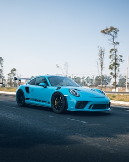 A vibrant blue McLaren on a scenic coastal road.