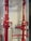 Two large red industrial pipes with pressure gauges and valves are mounted on a utility wall. The pipes have labels with numbers and are connected to other smaller pipes and devices.