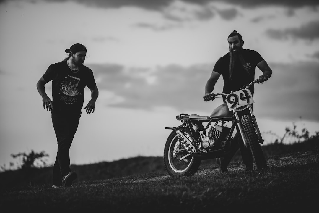man and woman riding motorcycle in grayscale photography