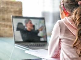 woman in pink long sleeve shirt sitting in front of macbook pro