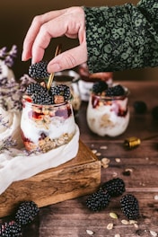 person holding ice cream cone with strawberry and blueberry