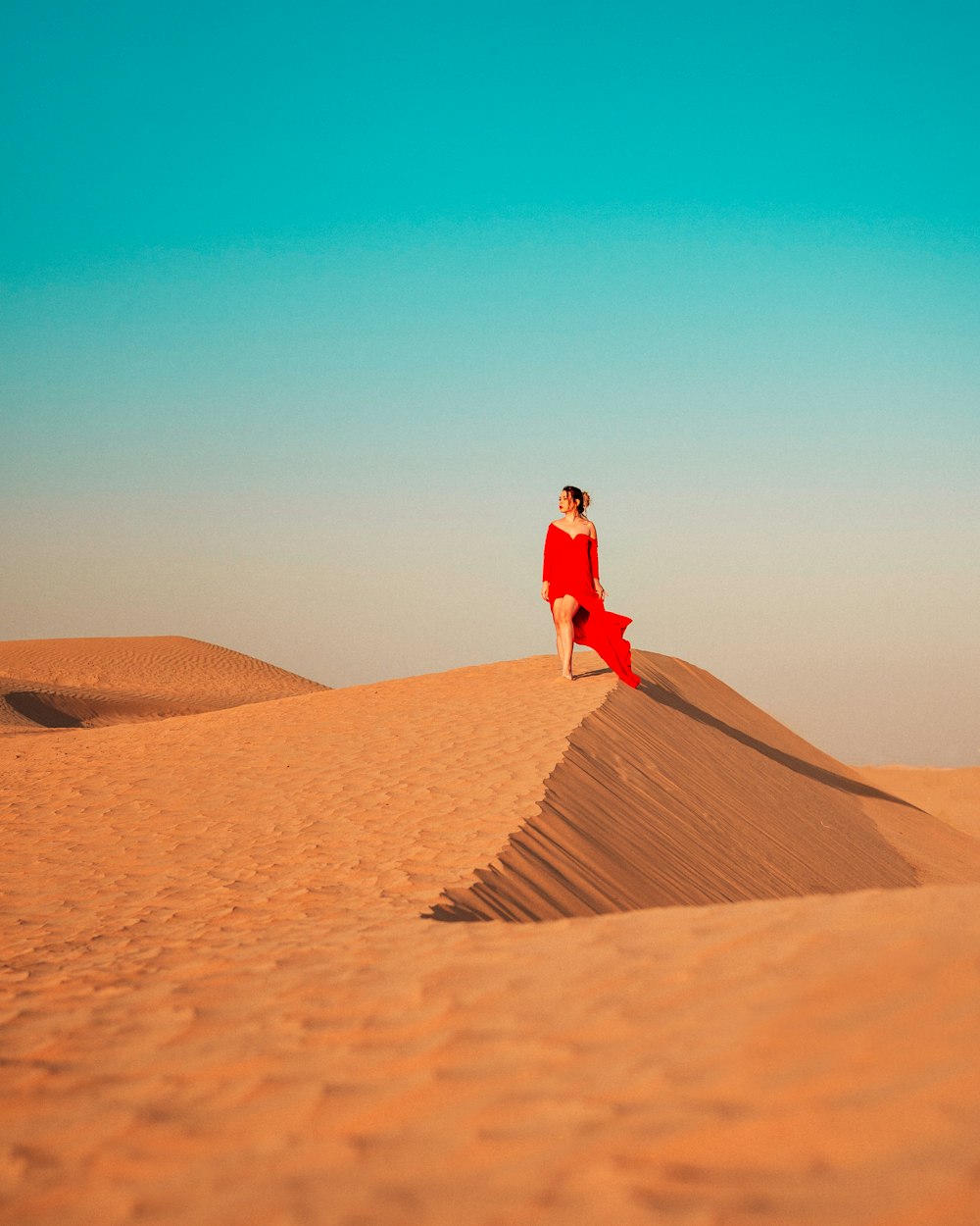 woman in red jacket walking on brown sand during daytime