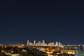 Denver skyline with the Rocky Mountains rising dramatically behind the city under a clear blue sky