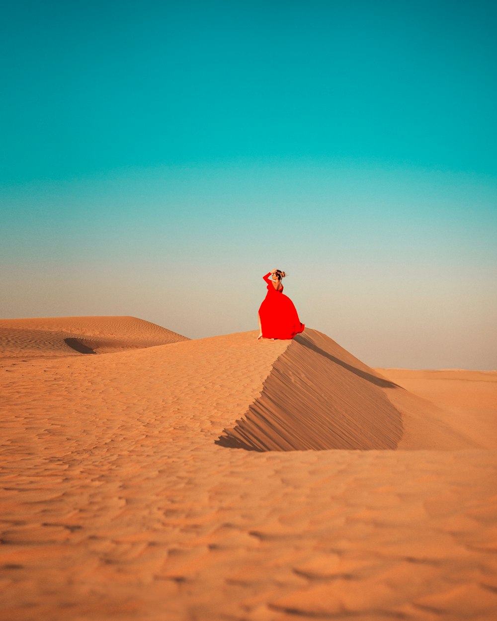 woman in red dress standing on brown sand during daytime