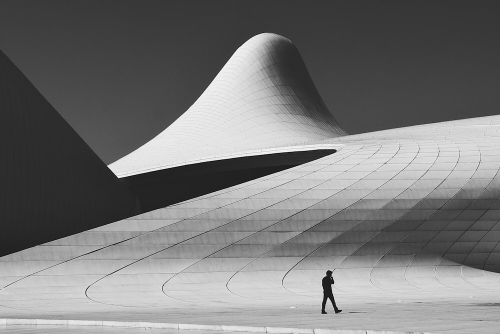 grayscale photo of man walking on road