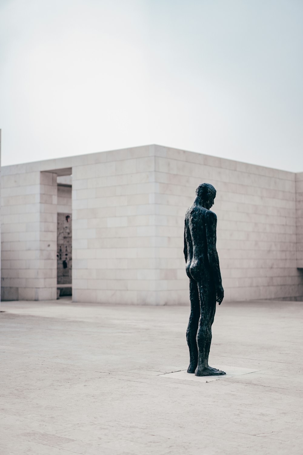 man in black jacket standing near white concrete building during daytime