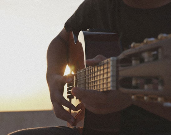 man in black crew neck t-shirt playing acoustic guitar