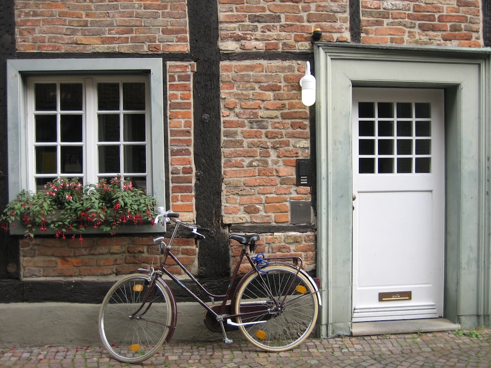 blue city bike parked beside brown brick wall