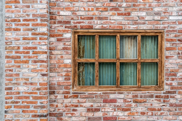 A row of colorful uPVC window frames displayed against a rustic brick wall.