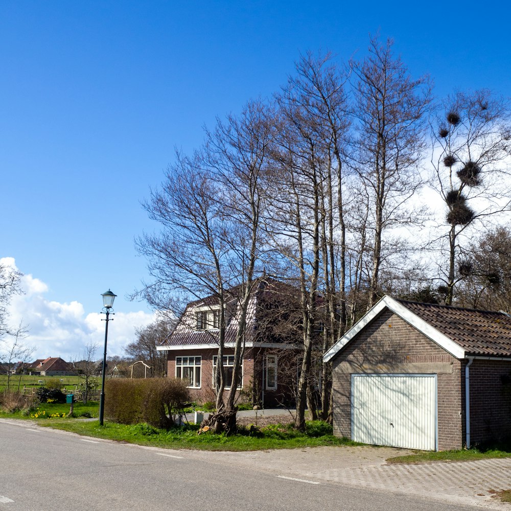 brown and white house near bare trees under blue sky during daytime