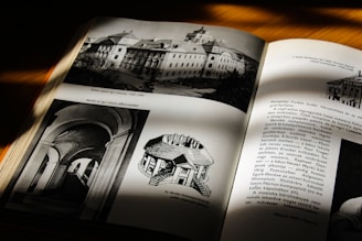 An open book under natural light, showing monochrome images of architecture and text. The left page displays architectural drawings and photographs, while the right page consists of textual content and a smaller image in the top right corner.