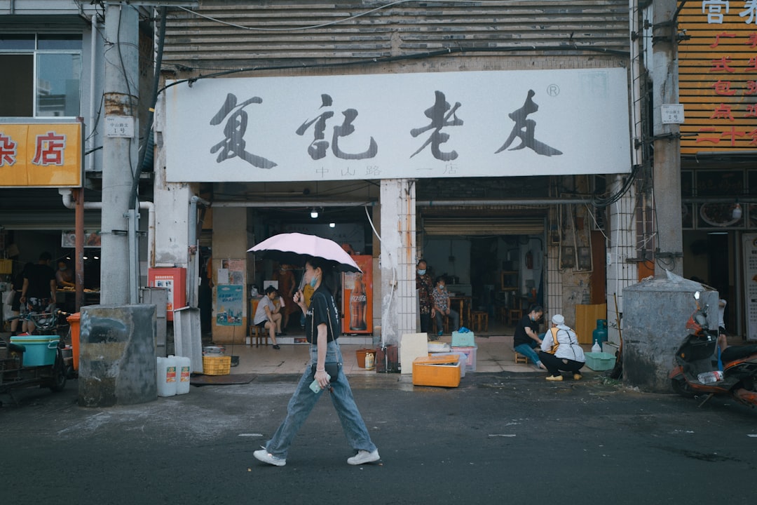 woman in black jacket and blue denim jeans walking on sidewalk during daytime