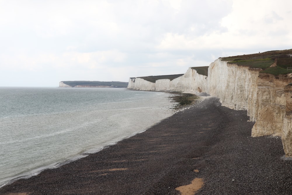 brown rocky mountain beside sea during daytime