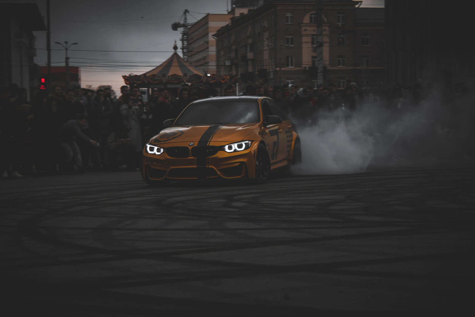 Orange BMW M3 drifting on a road with tire smoke