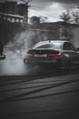 An in-game view of a custom car drifting on a wet street reflecting neon pink and black lights.