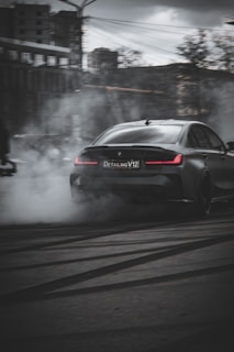 Dynamic shot of a modified car drifting on an urban street with smoke trailing behind