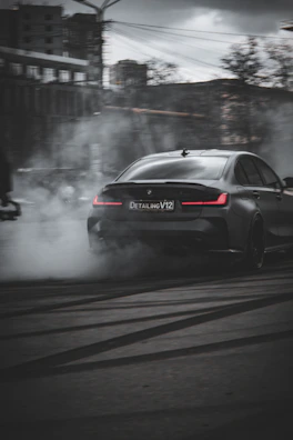 An in-game view of a custom car drifting on a wet street reflecting neon pink and black lights.
