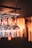 A set of wine glasses hang upside down from a rack, reflecting warm ambient lighting. The background is softly blurred, highlighting the clarity and elegance of the glassware.