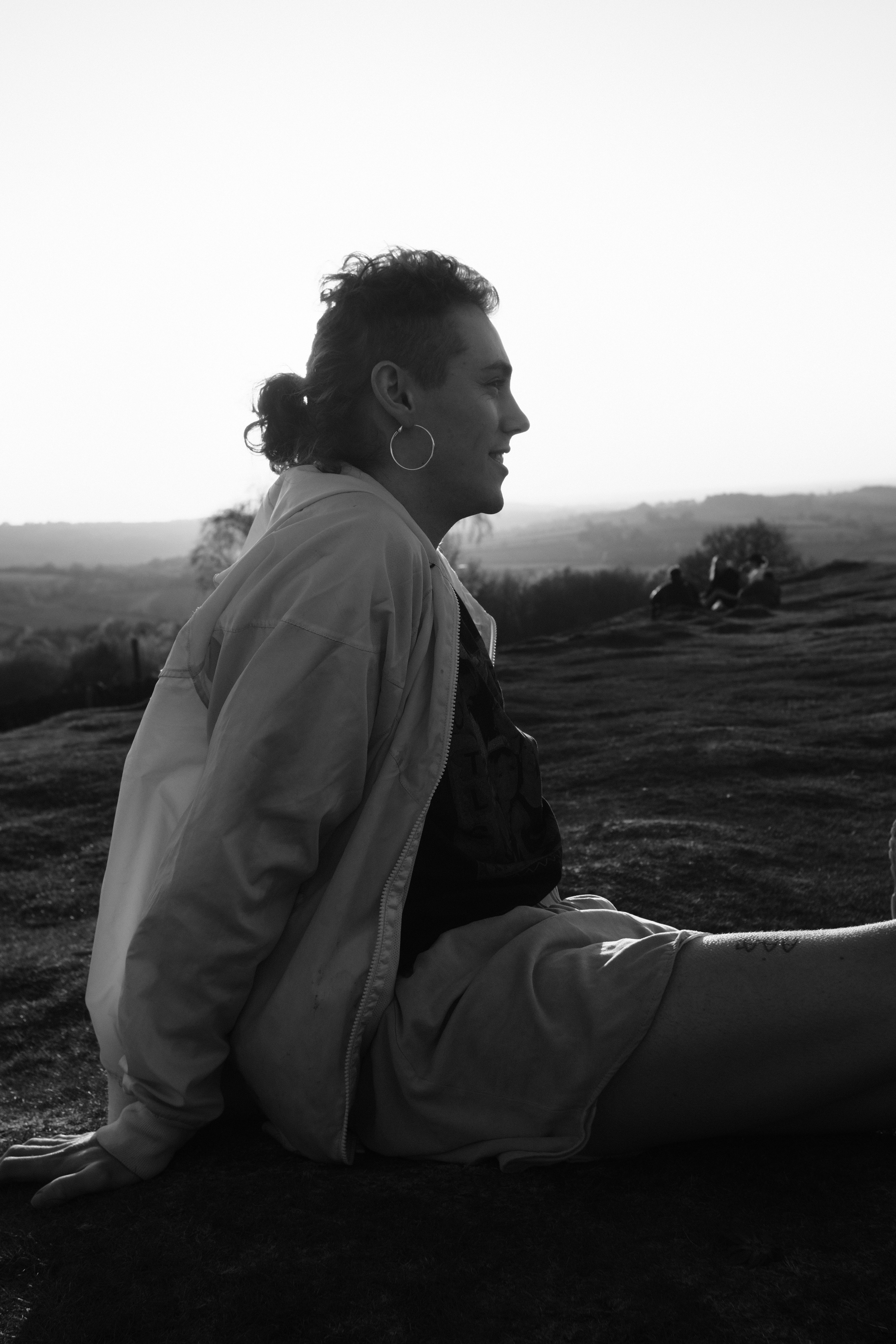 man in black jacket sitting on grass field