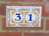 A freshly painted curb displaying a bold house number in bright white paint.