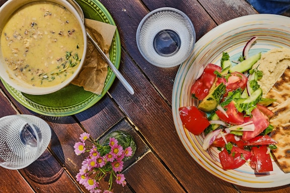A rustic wooden table set with bowls of fresh vegetables, herbal teas, and colorful salads.