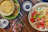 A rustic wooden table set with colorful ceramic bowls filled with fresh salad, sunlight streaming in.