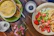 A rustic wooden table set with colorful ceramic bowls filled with fresh salad, sunlight streaming in.