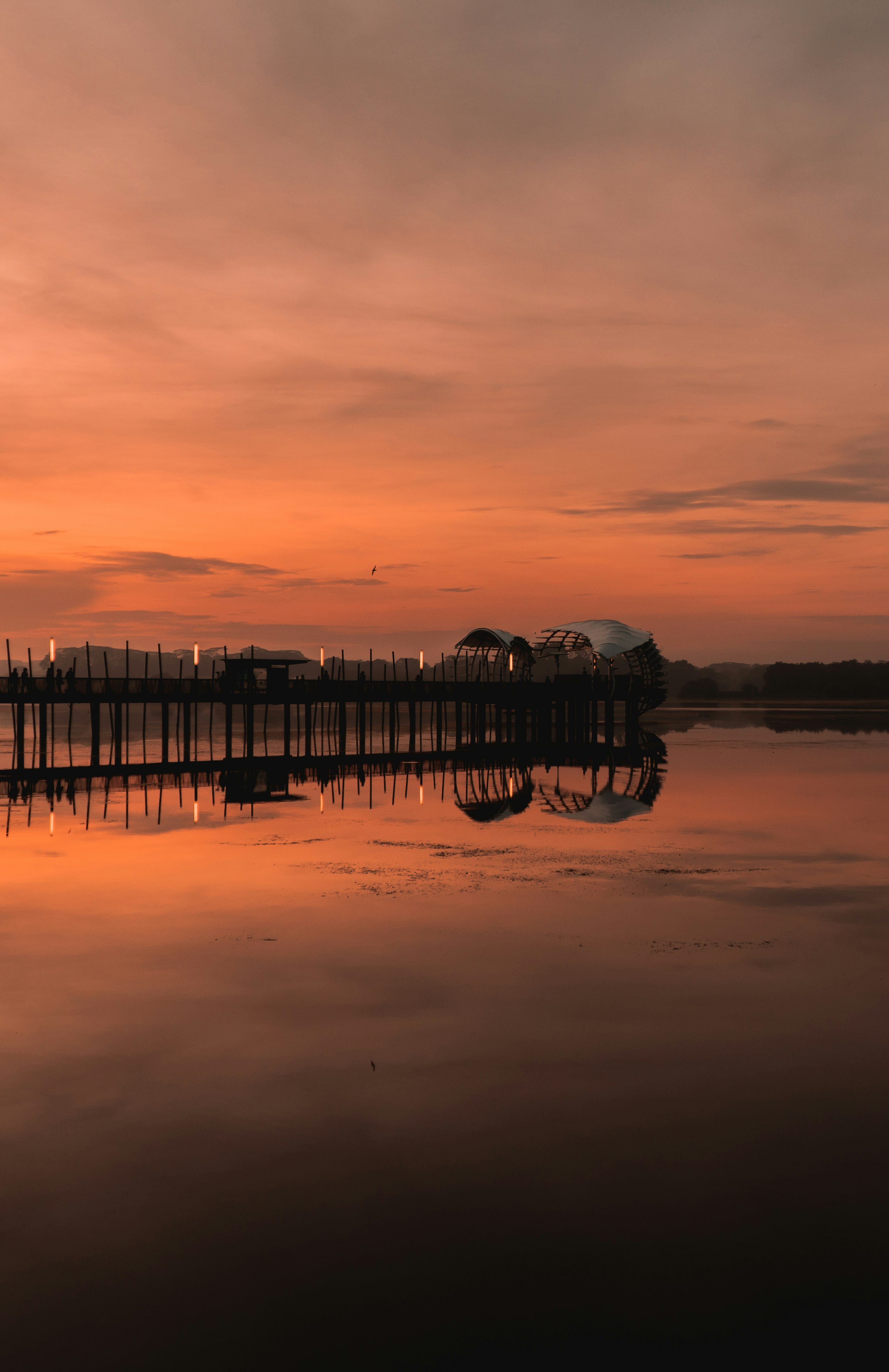 silhouette of dock on lake during sunset