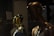 A display of mannequins with reflective golden surfaces in a dimly lit setting, creating a sleek and modern aesthetic. The foreground mannequin is bronze, while the others are gold, partially clothed, and arranged in proximity to each other, giving an impression of luxury and style.