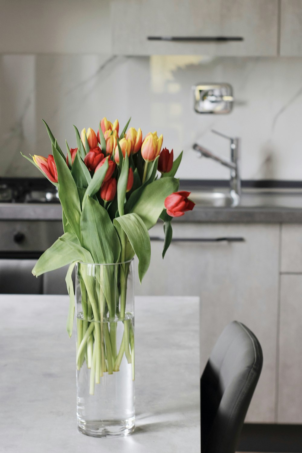 red and yellow tulips in clear glass vase