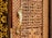 A detailed view of a wooden door with intricate carvings featuring geometric patterns and a prominent golden door handle shaped like a bird. The craftsmanship highlights traditional and ornate design elements.