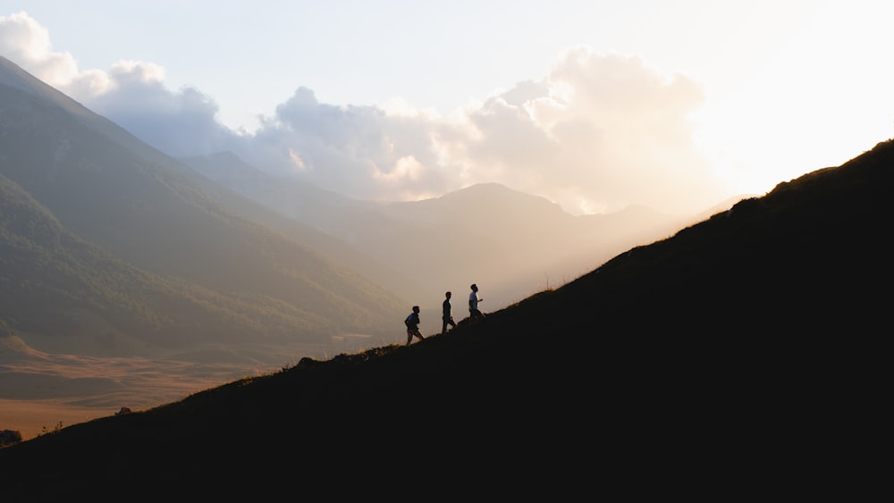 silhouette of 2 people standing on mountain during daytime