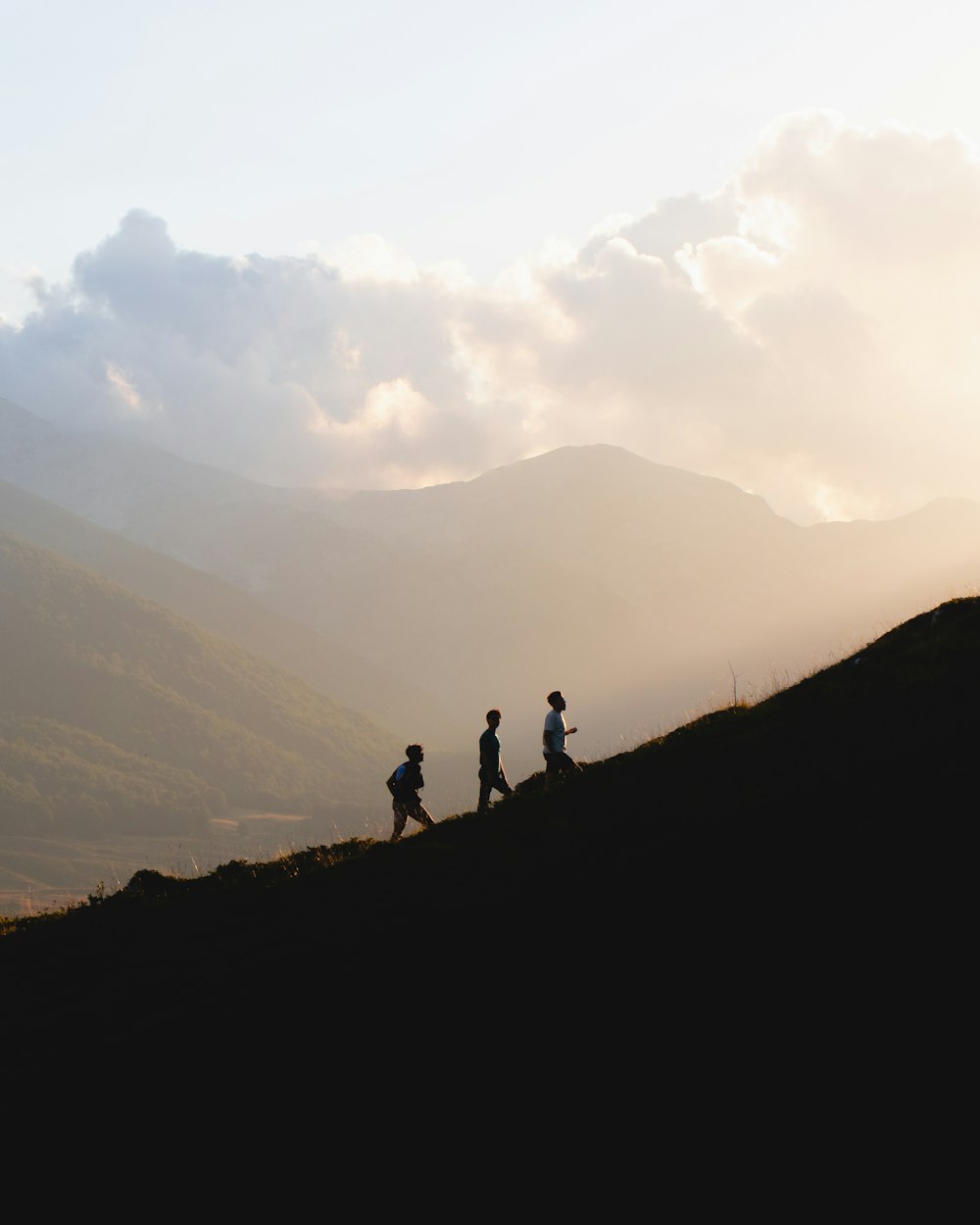 silhouette of 2 people standing on top of mountain during daytime