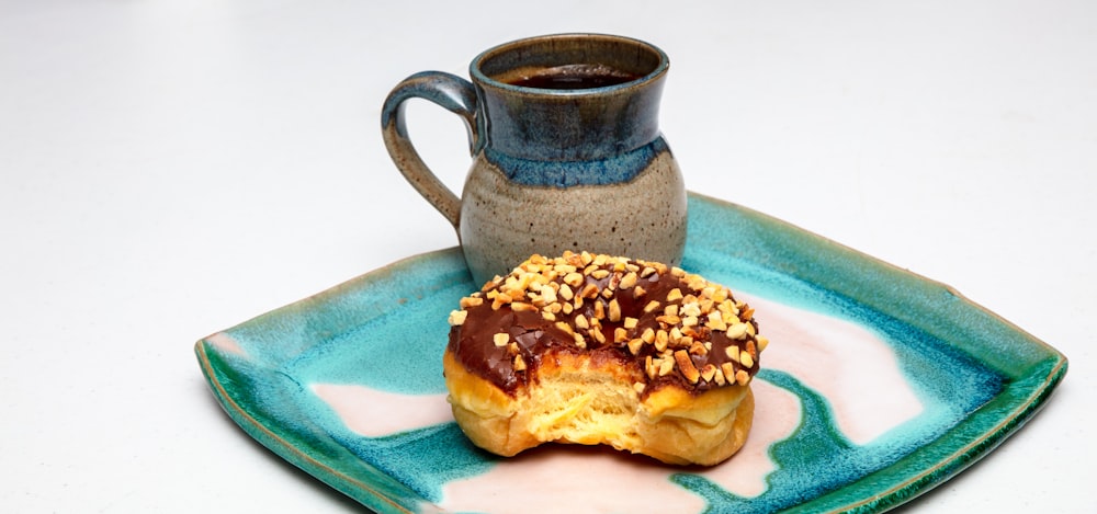 a doughnut on a plate next to a cup of coffee