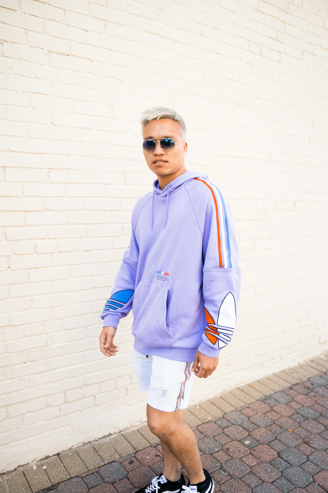 man in blue nike zip up hoodie standing beside white wall