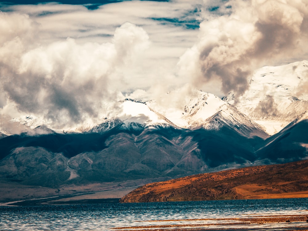 white clouds over snow covered mountain