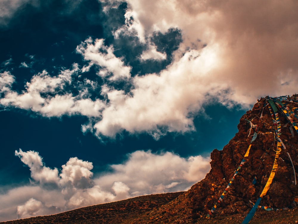 brown mountain under white clouds and blue sky during daytime