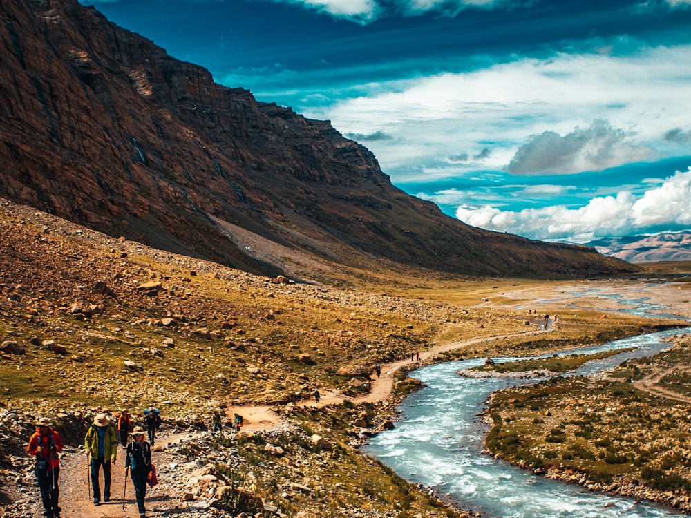 people walking on brown field near brown mountain under blue sky during daytime