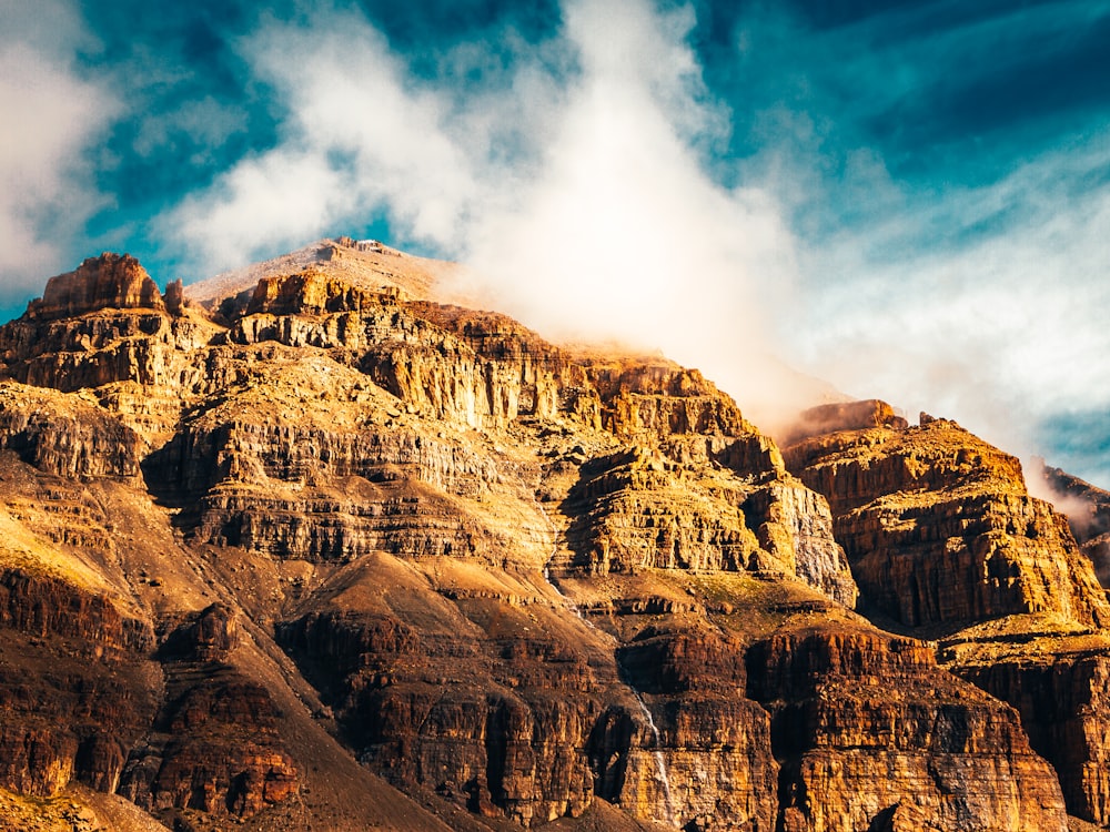 brown rocky mountain under white clouds and blue sky during daytime