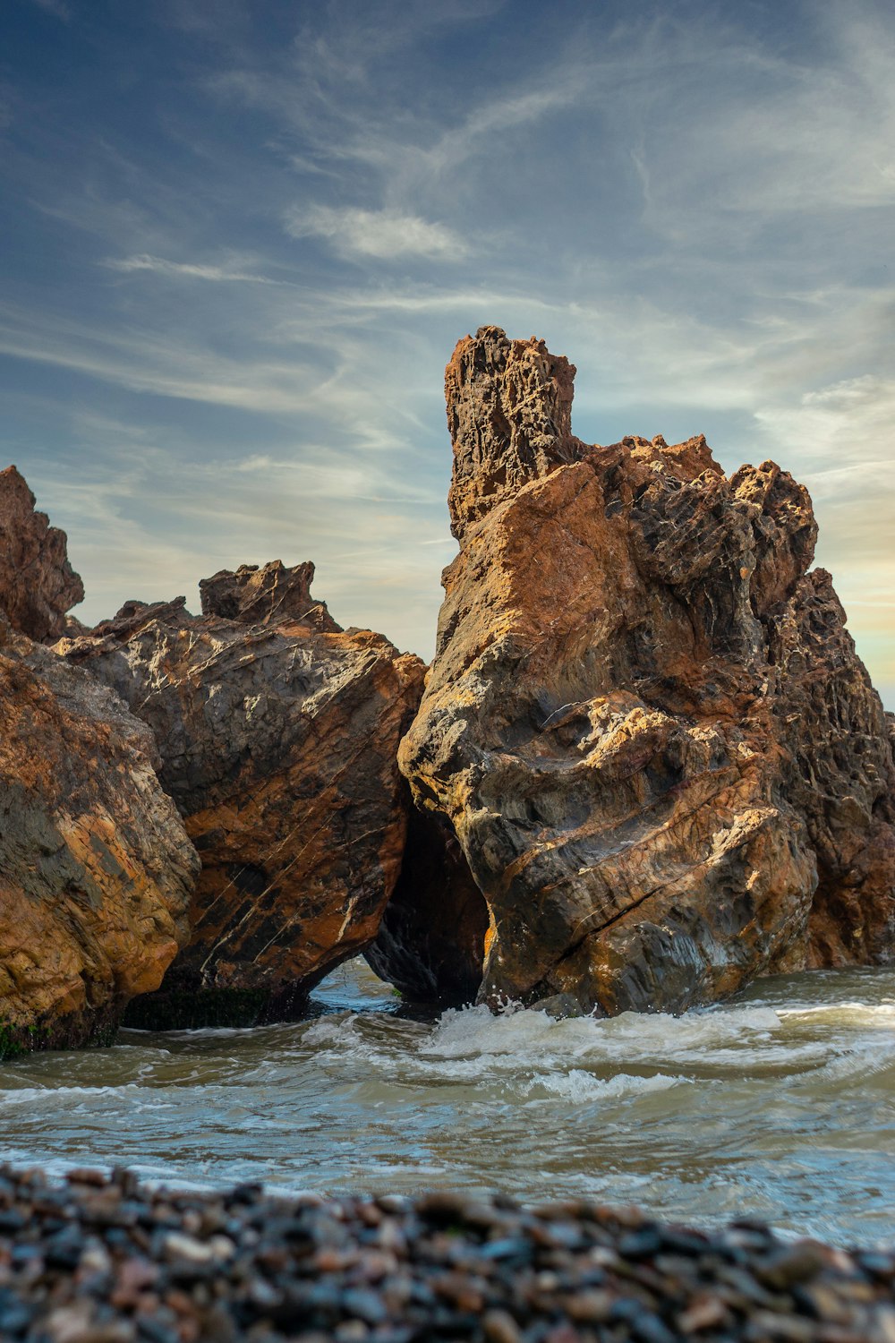 brown rock formation on sea under blue sky during daytime